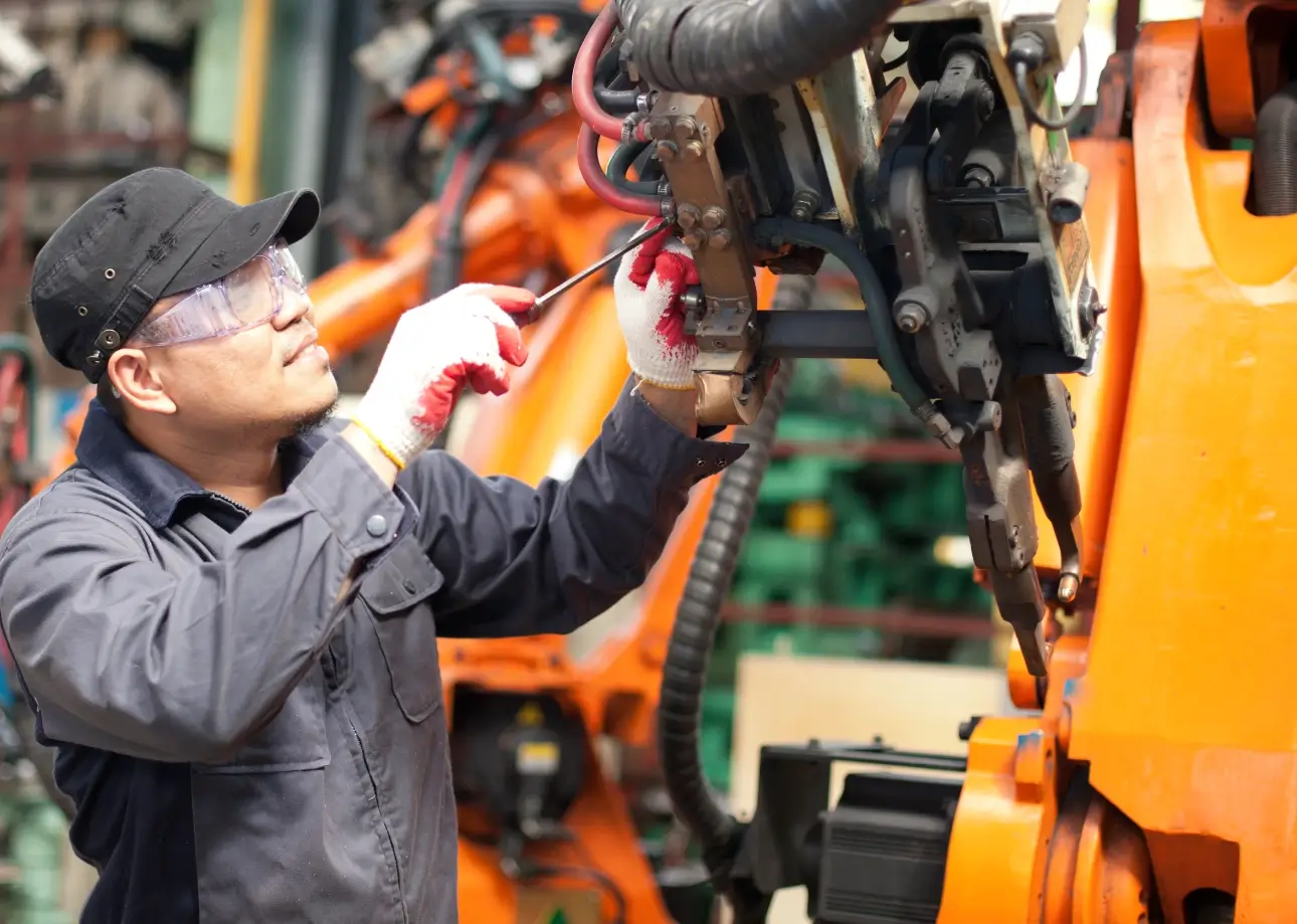 Worker repairing industrial machinery with tools.